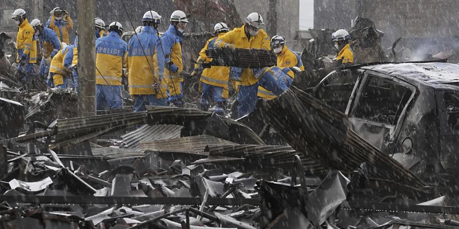 Polizeibeamte beseitigen die Trümmer eines Brandes auf einem Markt in der Präfektur Ishikawa. Foto: Uncredited/Kyodo News/AP/dpa - ACHTUNG: Nur zur redaktionellen Verwendung und nur mit vollständiger Nennung des vorstehenden Credits