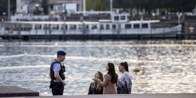 Ein Polizist spricht mit Personen über die Regeln im Zusammenhang mit dem Coronavirus. Polizei