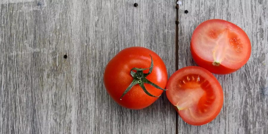 Zwei Tomaten  liegen auf einem Tisch.