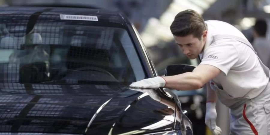 Ein Werksmitarbeiter kontrolliert in einer Produktionshalle von Audi an einem Bandende einen A8. Foto: picture alliance / dpa/Symbolbild