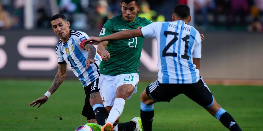 Boliviens Hector Cuellar in Aktion gegen die Argentinier Angel Di Maria (l) und Nahuel Molina (21).