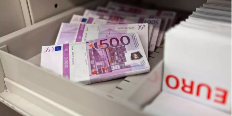 Mehrere Bündel von Euro-Banknoten liegen in einem Banktresor.