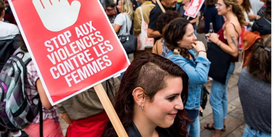 Eine Frau an der Demonstration in Genf gegen Gewalt an Frauen, die durch die Tragödie der fünf verprügelten Frauen ausgelöst wurde. Auf dem Schild steht: Stoppt die Gewalt gegen Frauen.