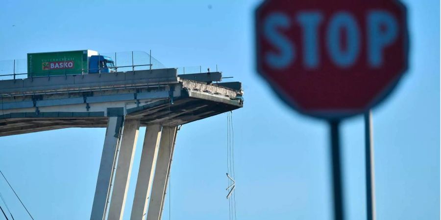 Der grün-blaue Lastwagen der lokale Supermarktkette Basko steht auch am Tag nach dem Einsturz der Morandi-Brücke in Genua (I) noch an der selben Stelle: wenige Meter vor dem Abgrund.