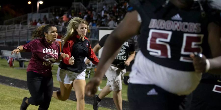 Nachdem bei einem Footballspiel an der Palm Beach Central High School Schüsse gefallen sind, flüchten Menschen aus einem Stadion.