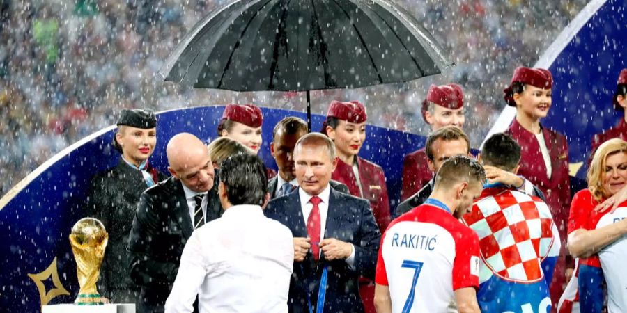 Ein Platzregen zur Unzeit: Während der Siegerehrung im Moskauer Luschniki-Stadion beginnt es auf einmal zu regnen. Wladimir Putin steht bald im Trockenen, doch alle anderen werden nass.