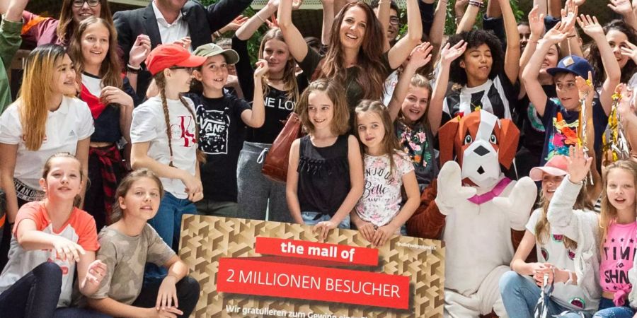 In der Mitte: Mutter Melanie Arn und ihre Kinder Ayva und Lyah posieren hinter dem Schild. Einer von ihnen ist der zweimillionste Mall-Besucher.