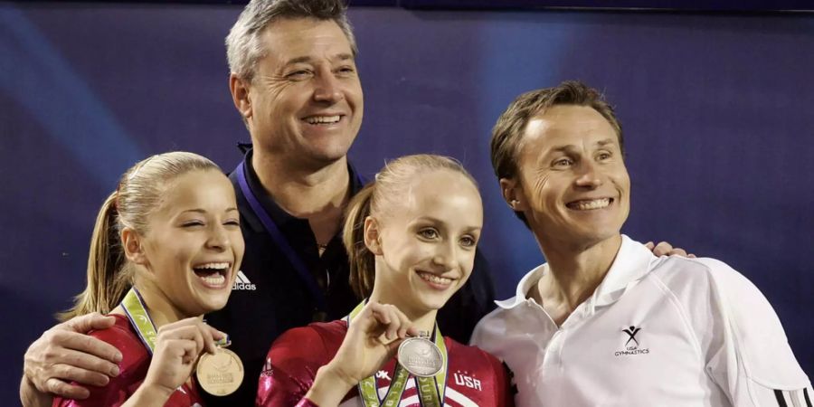 Die Turnerinnen Alicia Sacramone (links) und Anastasia Liukin (Mitte) posieren mit ihren Trainern Mihai Brestyan (links) und Valeri Liukin an den Weltmeisterschaften in Melbourne (2005).