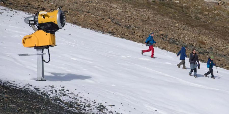 Schon im Oktober: Wanderer sind auf Kunstschnee unterwegs, am Freitag, 7. Oktober 2016, auf dem Weissfluhjoch in Davos. Die tiefen Temperaturen erlauben bereits die künstliche Beschneiung.