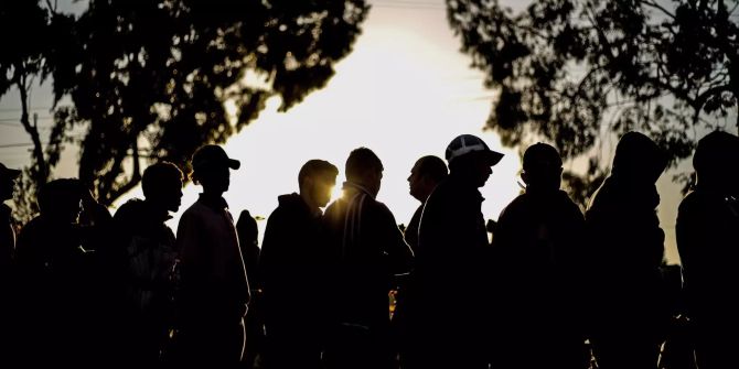 Einige Migranten der Karawane stehen bei einer Unterkunft in Tijuana Schlange.