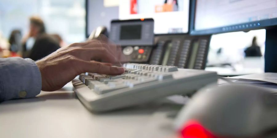 Ein Mann tippt einem Büro auf einer Tastatur.