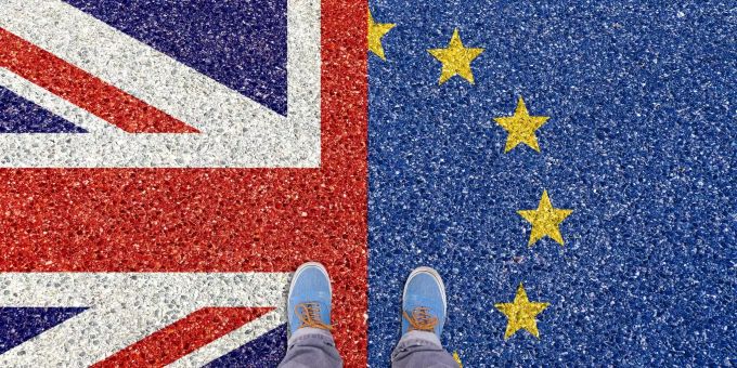 Ein Mann steht auf den Flaggen von Grossbritannien und der EU. Ein Mann steht auf den Flaggen von Grossbritannien und der EU.