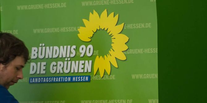 Ein Mitarbeiter der hessischen Grünen schiebt einen Aussteller von Bündnis 90/ Die Grünen zurecht.