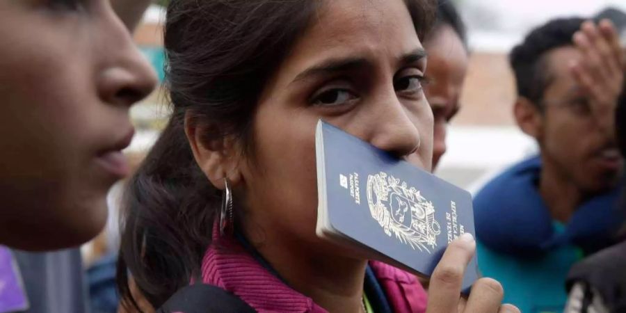 Eine Migrantin aus Venezuela hält ihren Pass in der Hand.