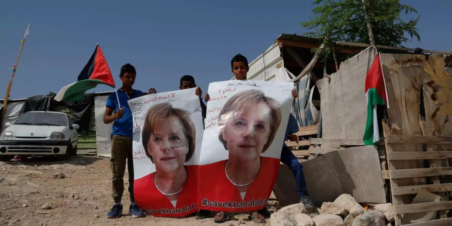 Palästinensische Kinder halten im Beduinendorf Chan Al-AhmarPoster mit einem Porträt der deutschen Bundeskanzlerin Angela Merkel, auf denen #savekhanalahmar (#rettekhanalahmar) steht.