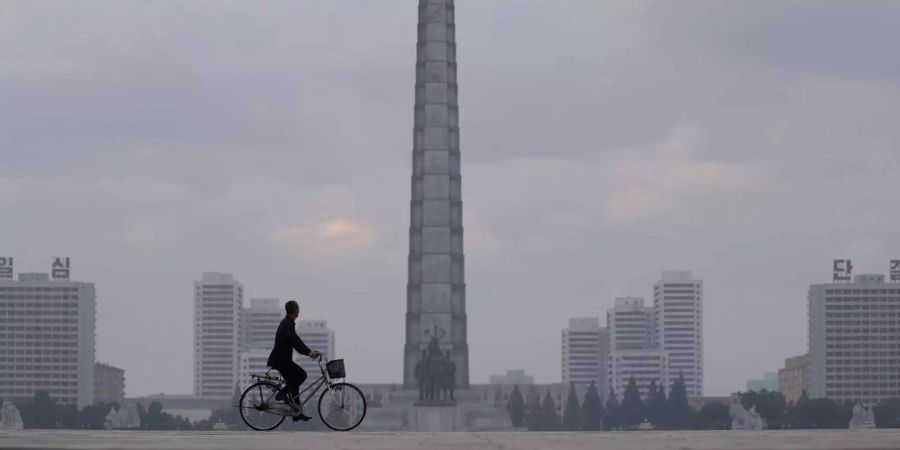 Ein Mann fährt mit seinem Fahrrad am Monument der Chuch·e-Ideologie in Pjöngjang vorbei.