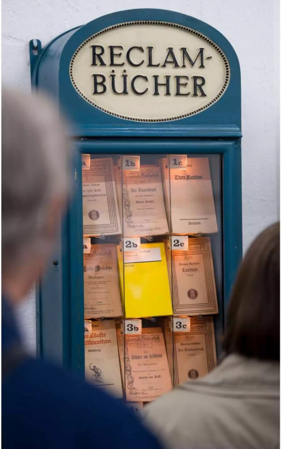 Teilnehmer einer Vorbesichtigung stehen im Reclam-Museum in Leipzig vor dem Nachbau eines Reclam-Bücherautomaten, wie er in den Jahren 1912 bis 1917 unter anderem auf Bahnhöfen zu finden war.