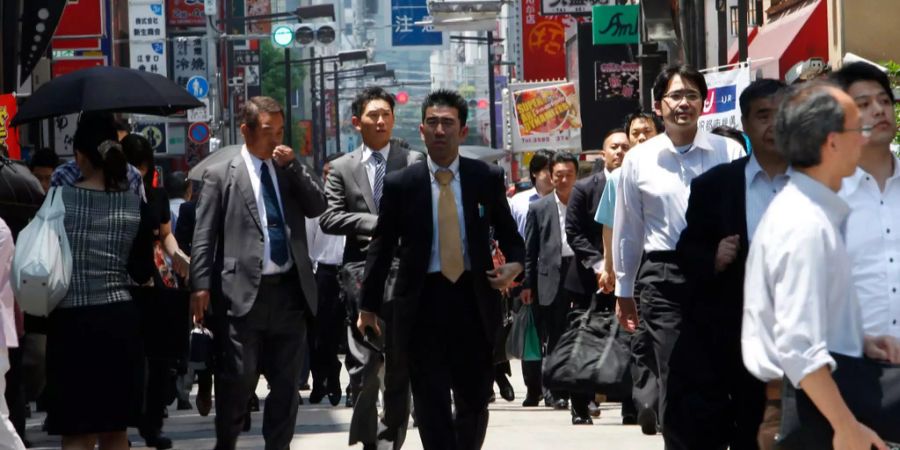 Büroangestellte schlendern durch eine Strasse in Japan.