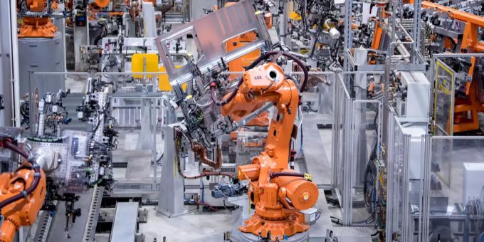 Erfreuliche Neuigkeiten für Angestellte der Maschinen-, Elektro- und Metallindustrie (MEM). Orange Roboter arbeiten in einer Firma
