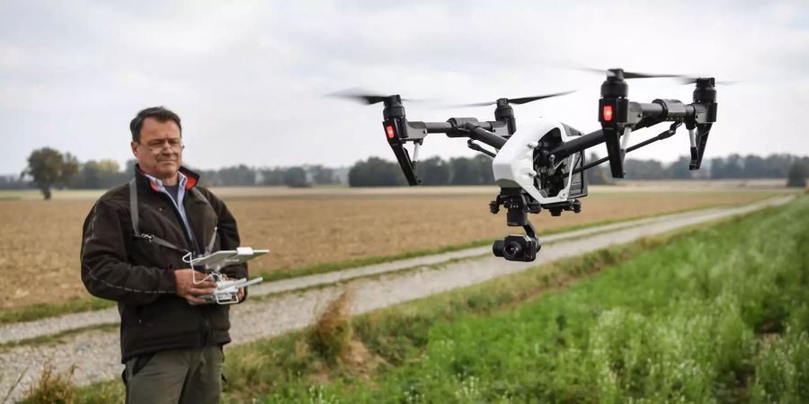 Ein Mann steuert auf einer Wiese eine Drohne des Typs Inspire 1 des Herstellers dji.