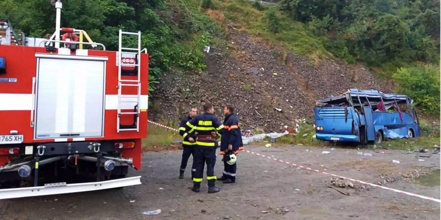 In diesem Handout-Foto des bulgarischen Innenministeriums stehen Feuerwehrleute in der Nähe eines zuvor einen Abhang hinabgestürzten Busses.
