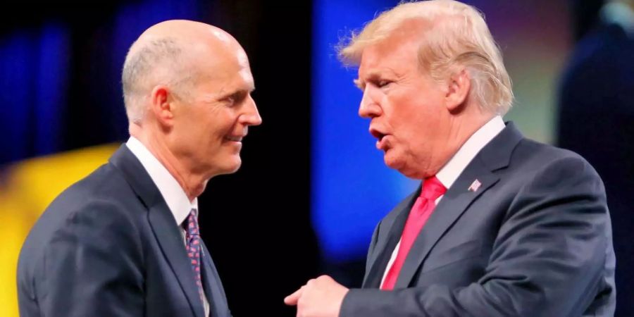 Floridas Governeur Rick Scott und Donald Trump schütteln sich bei einem Treffen die Hand.