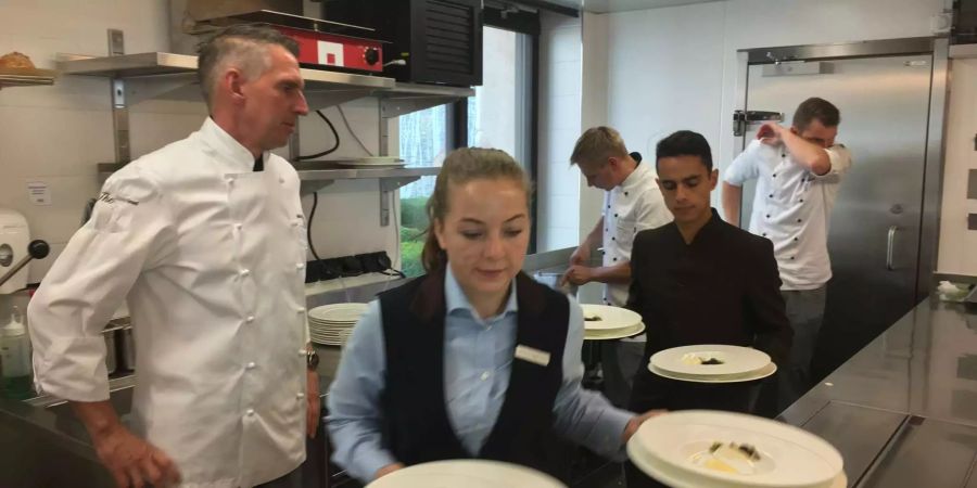 Der Chefkoch schaut seinem Team über die Schulter.