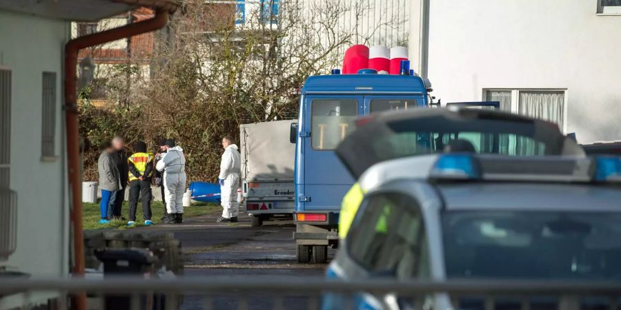 Polizisten stehen auf dem umzäunten Grundstück.