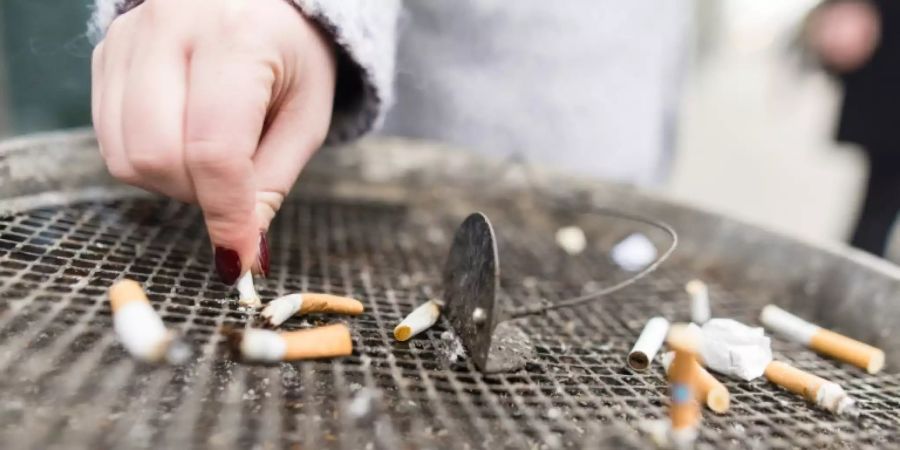 Eine Frau drückt eine Zigarette in einem Aschenbecher aus