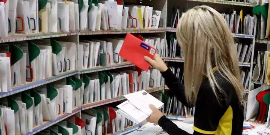 Im Zustellstützpunkt von Deutscher Post und DHL werden Briefe sortiert. Foto: Bernd Wüstneck/Illustration