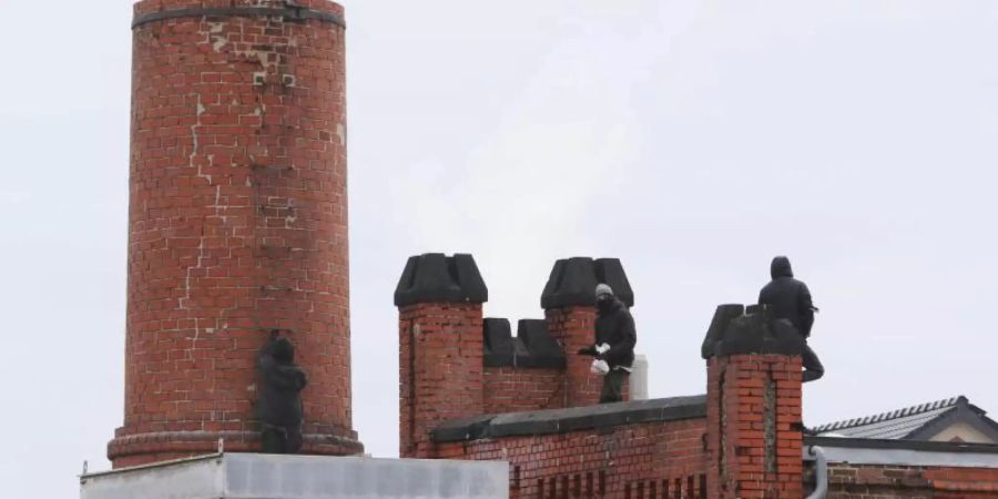 Vermummte Personen stehen auf dem Schornstein und dem Dach des Schlachthofes. Rund 30 Personen haben den Schlachthof besetzt. Foto: Ralf Roeger