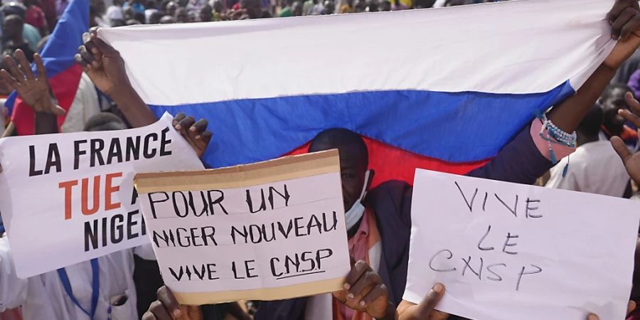 Teilnehmende des Marsches in Niamey im Niger, zu dem Anhänger des Putsches aufgerufen haben, halten verschiedene Plakate Foto: Sam Mednick/AP/dpa