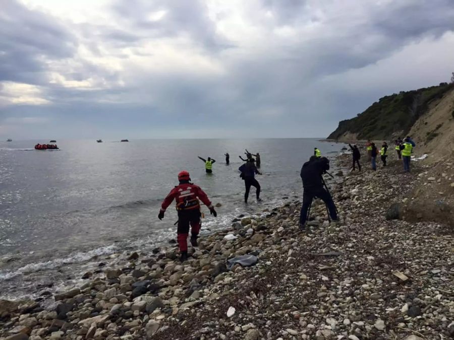 Geflüchtete erreichen einen Strand auf Lesbos in Griechenland und werden von Hilfe empfangen.