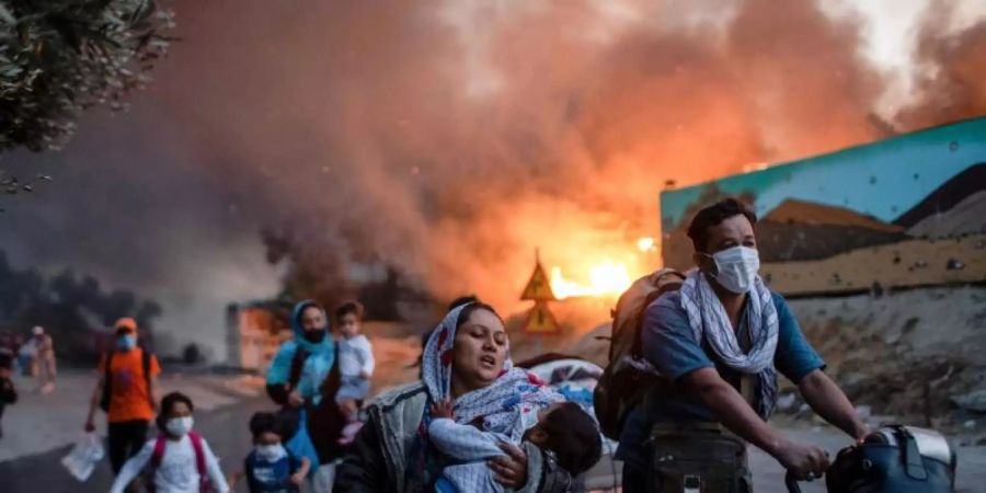 Migranten fliehen im September 2020 aus dem brennenden Flüchtlingslager Moria auf Lesbos. Foto: Petros Giannakouris/AP/dpa