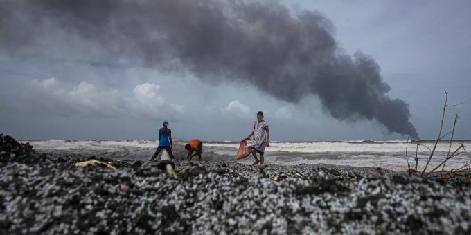Menschen gehen über den mit Mikroplastik verschmutzten Strand vor dem Wrack des brennenden Schiffes MV "X-Press Pearl" aus Singapur, das vor dem Hafen von Colombo in Kapungoda, einem Außenbezirk von Colombo, vor Anker liegt. sri lanka