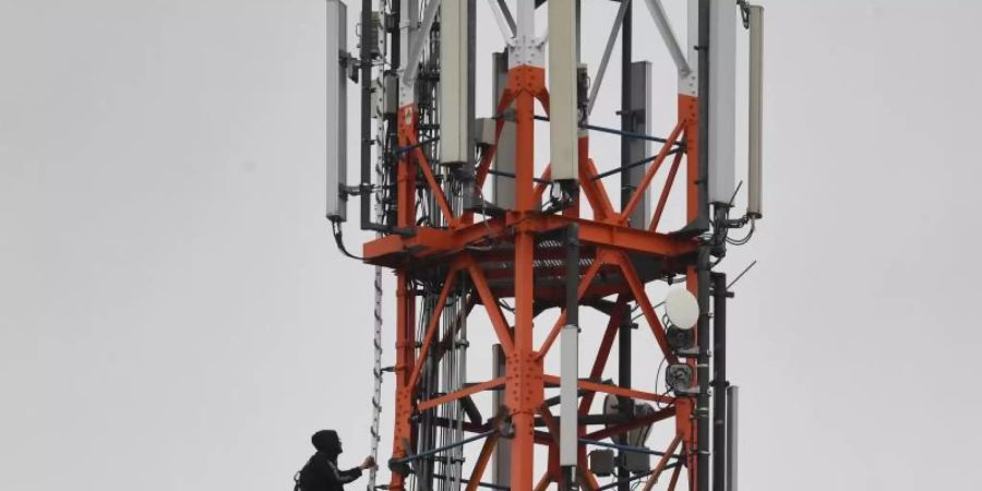 Ein Techniker klettert an einem Funkmast neben Mobilfunkantennen für den Mobilfunkstandard 5G. Foto: Stefan Sauer/zb/dpa