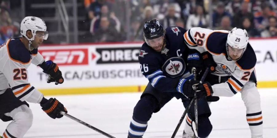 Blake Wheeler (M.) von den Winnipeg Jets im Zweikampf mit Leon Draisaitl (r). Foto: Fred Greenslade/The Canadian Press/AP/dpa