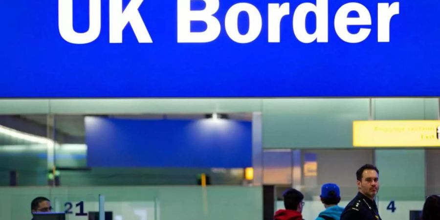 Grenzbeamte stehen am Flughafen Heathrow in London unter einem Schild mit der Aufschrift «UK Border». Foto: Andrew Cowie/EPA/dpa