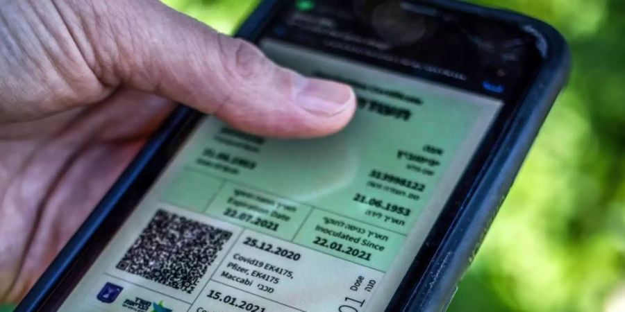 Weg zur Freiheit: Ein israelischer Mann hält ein Smartphone in der Hand, auf dem der sogenannte grüne Pass abgebildet ist. Foto: Ilia Yefimovich/dpa