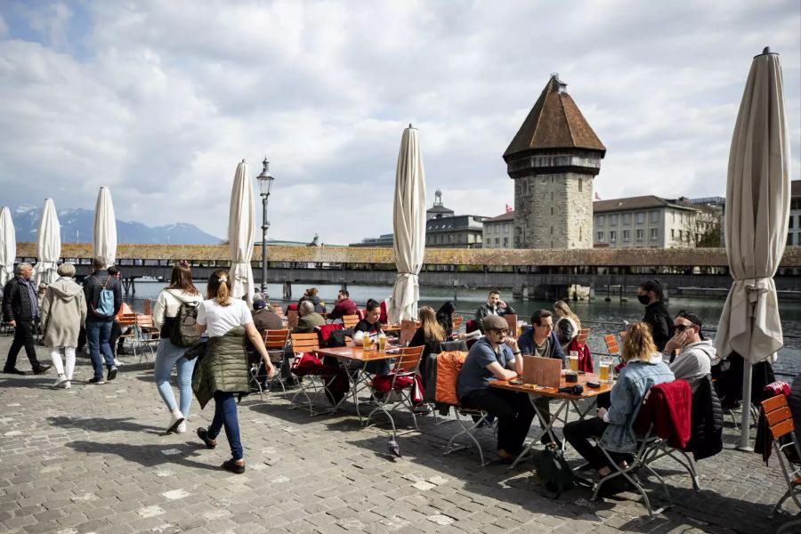 Gäste sitzen im Aussenbereich eines Restaurants in Luzern an der Reuss.