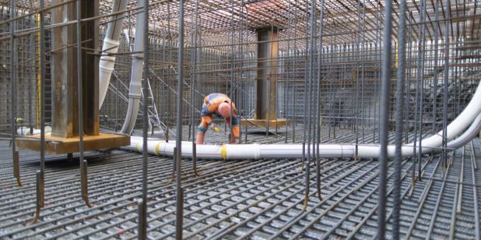 Ein Bauarbeiter installiert Thermometer im Stahl der Armierung des Betonsockels. Baustelle