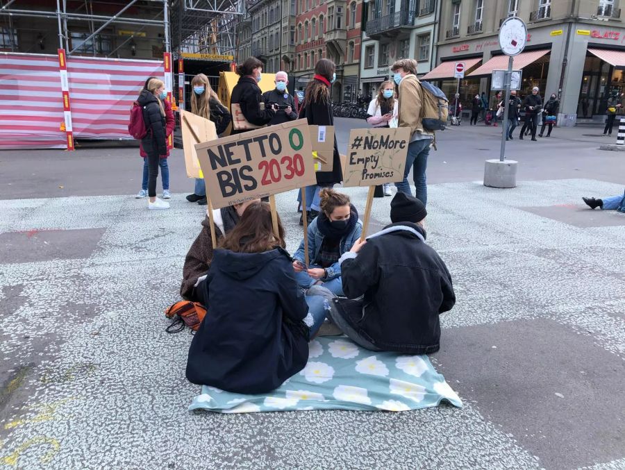 Die Klimaaktivisten sammeln sich in kleinen Gruppen auf dem Boden.