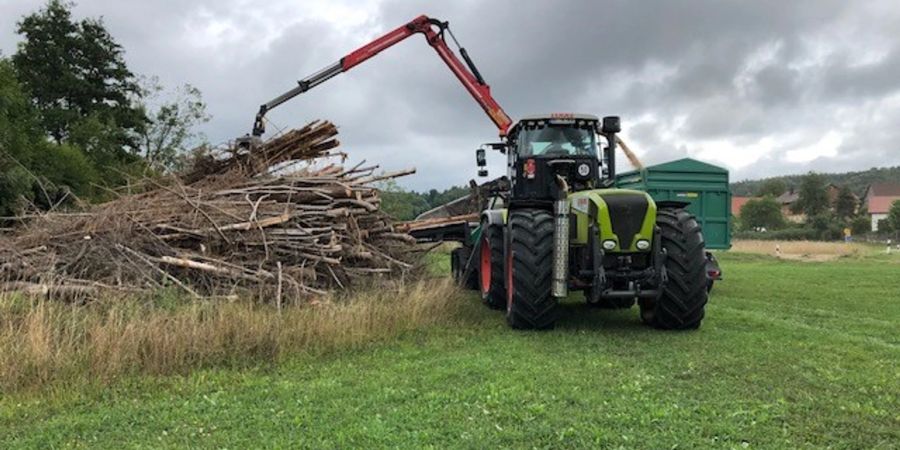 Aus Holz werden Hackschnitzel gehäckselt. Das Holz wird mit einem Kran und einer Zange in den Häcksler geschoben.