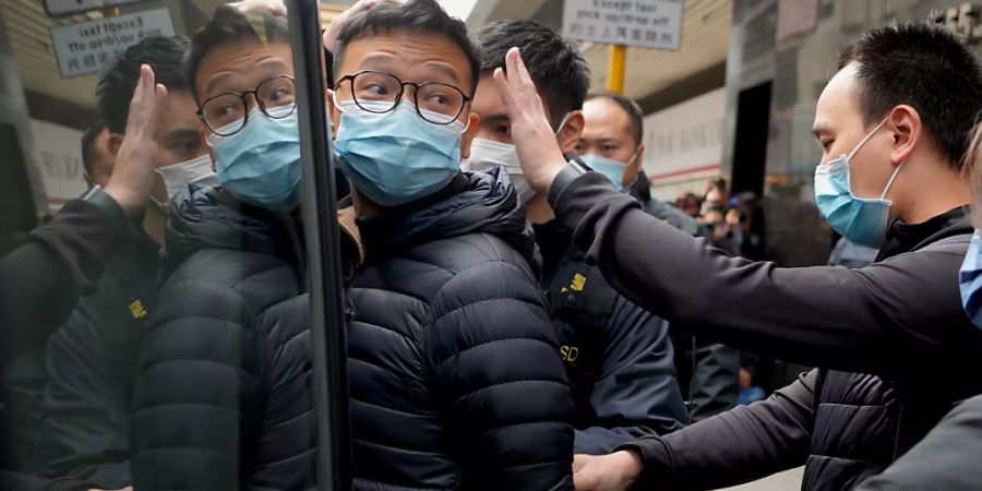 dpatopbilder - Der Herausgeber von «Stand News» Patrick Lam (l) wird von Polizeibeamten in einen Lieferwagen eskortiert. Mehrere Journalisten und ehemalige Mitarbeiter des pro-demokratischen Mediums wurden in Hongkong festgenommen. Foto: Vincent Yu/AP/dpa