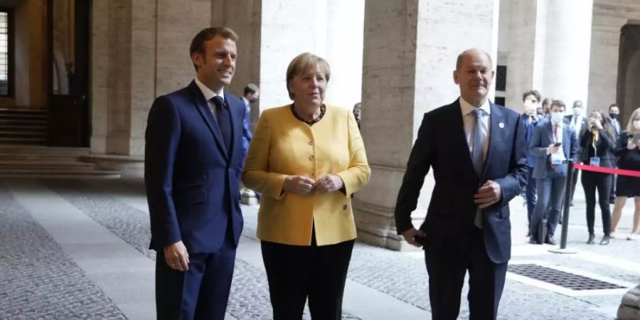 Emmanuel Macron (l-r), Präsident von Frankreich, begrüsst Angela Merkel (CDU), geschäftsführende Bundeskanzlerin, und Olaf Scholz (SPD), Bundesfinanzminister und Kanzlerkandidat, vor einem Treffen der Europäischen Union und der Afrikanischen Union in der französischen Botschaft. Foto: Gregorio Borgia/Pool AP/dpa