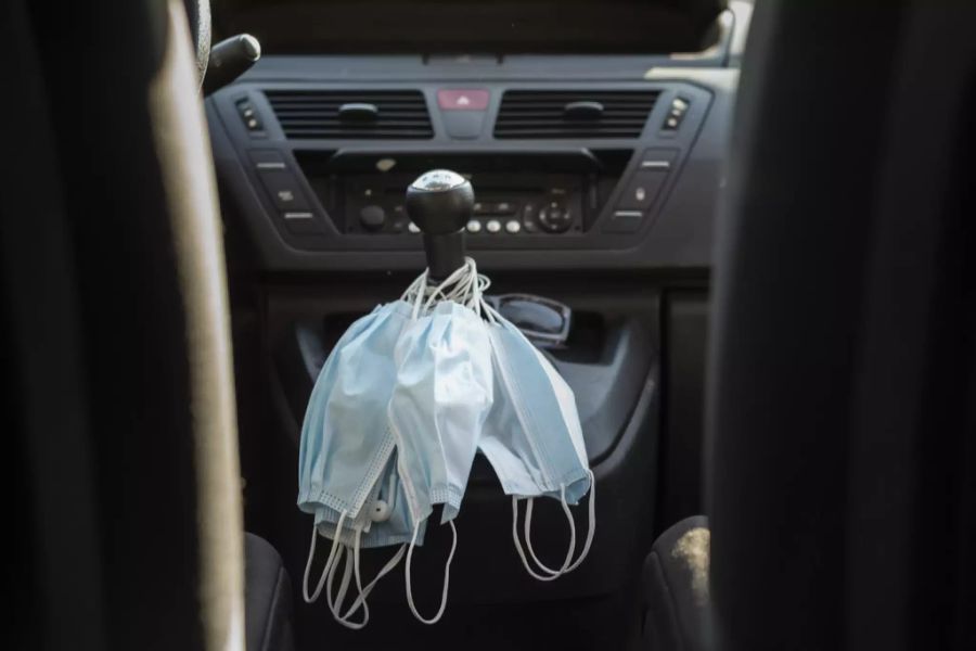 Mehrere OP-Masken liegen auf dem Schalthebel eines Autos.