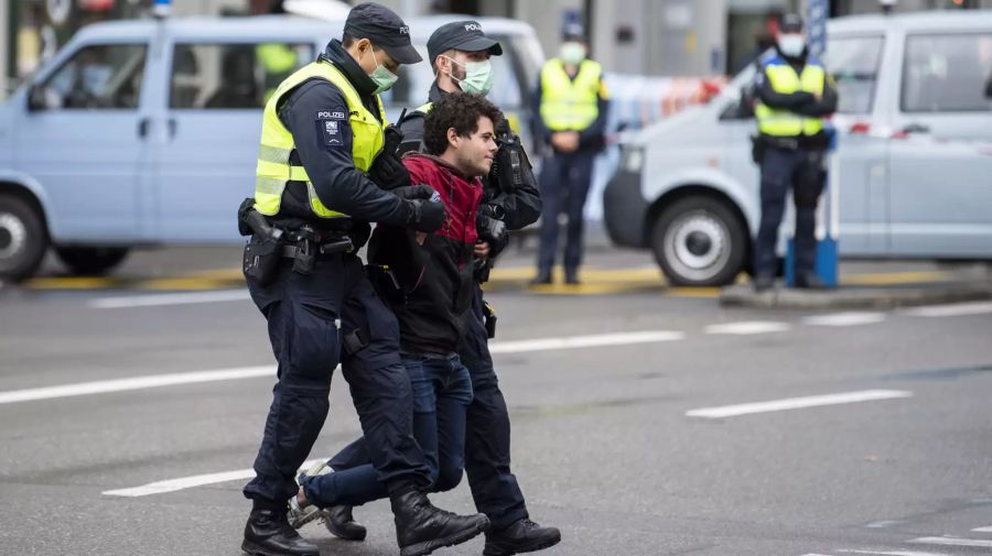 Ein Aktivist wird von zwei Polizisten weggetragen.