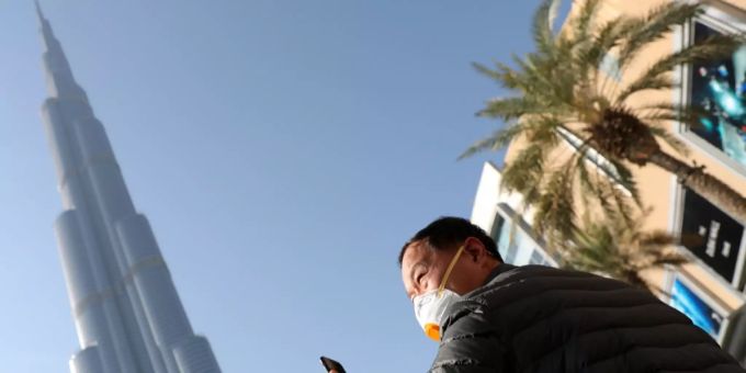 Ein Mann mit Gesichtsmaske steht vor dem höchsten Gebäude der Welt, dem Burj Khalifa in Dubai. vereinigte arabische emirate