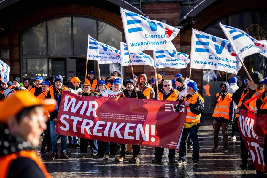 27.03.2023, Bremen: Demonstranten der Eisenbahn- und Verkehrsgewerkschaft (EVG) stehen mit Plakaten vor dem Hauptbahnhof. Mit einem grossangelegten bundesweiten Warnstreik haben die Gewerkschaften EVG und Verdi am Montag weite Teile des öffentlichen Verkehrs lahmgelegt. Foto: Sina Schuldt/dpa +++ dpa-Bildfunk +++