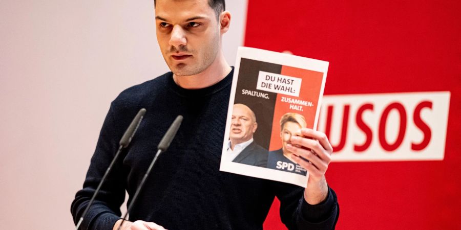 Kubilay Yalcin hält auf der Landesdelegiertenkonferenz der Jusos Berlin ein Wahlplakat mit Giffey und Wegner in die Höhe.